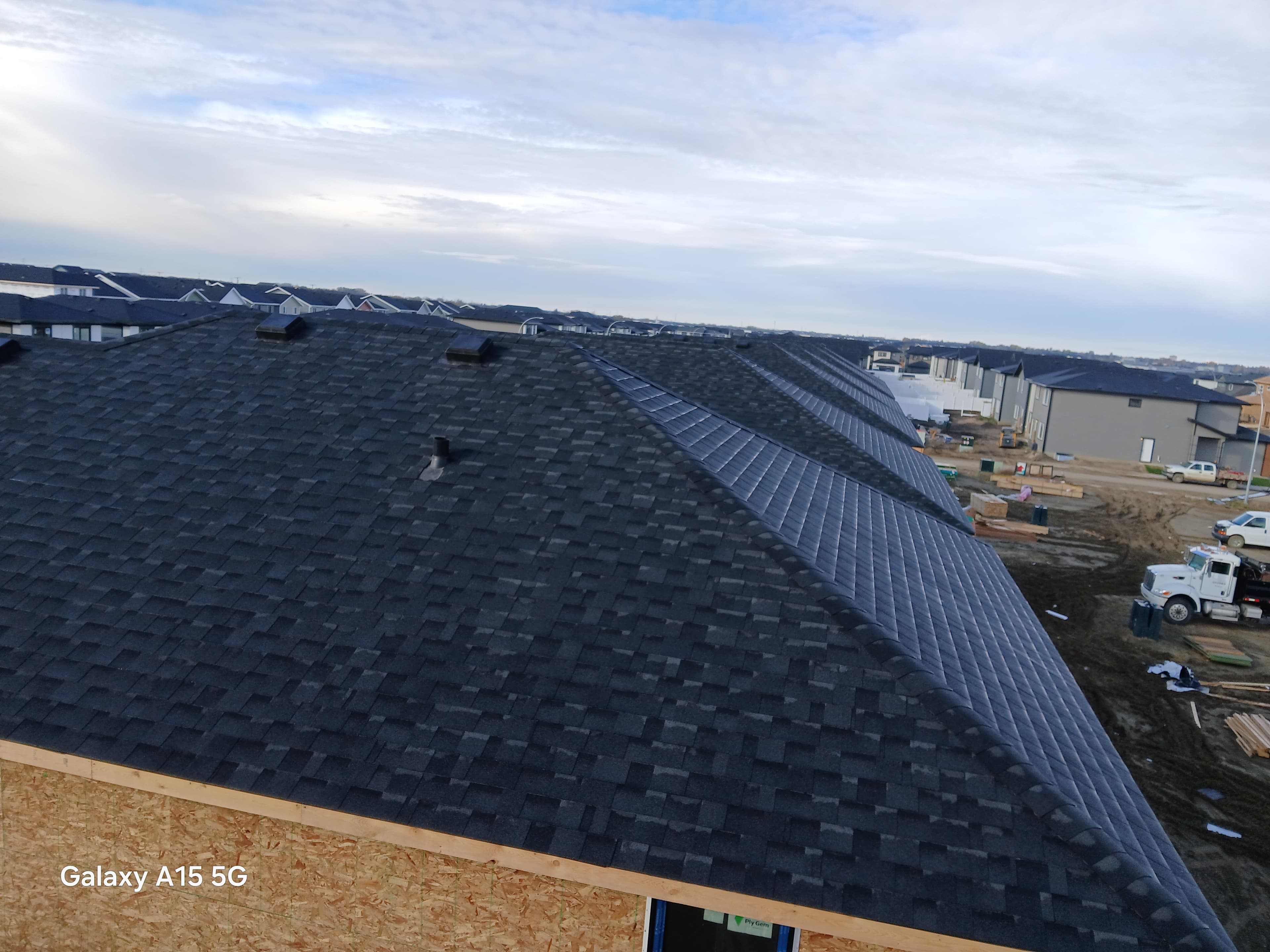 Dark grey shingled roof of a house under construction in a new residential development.