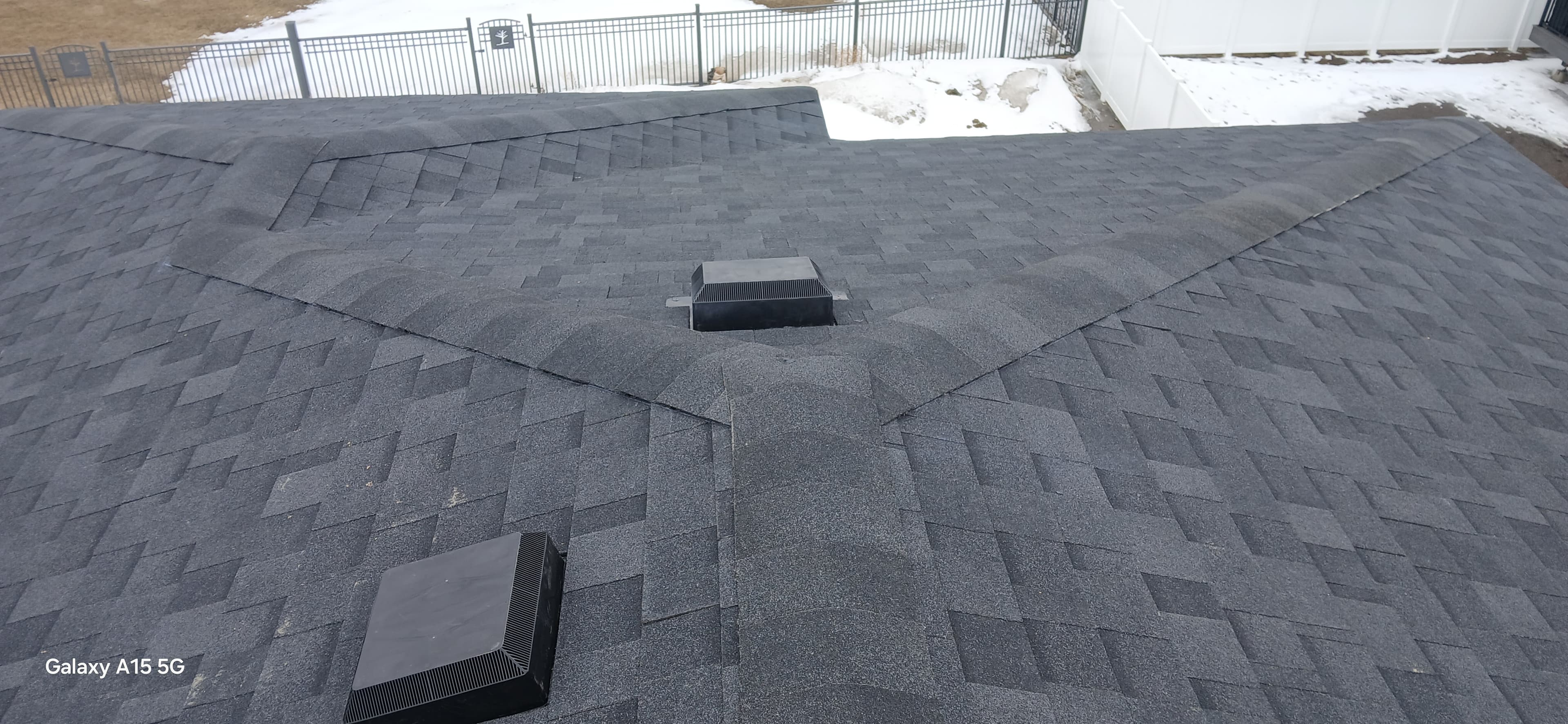 Dark gray asphalt shingle roof with multiple ridges, valleys, and two black box vents.